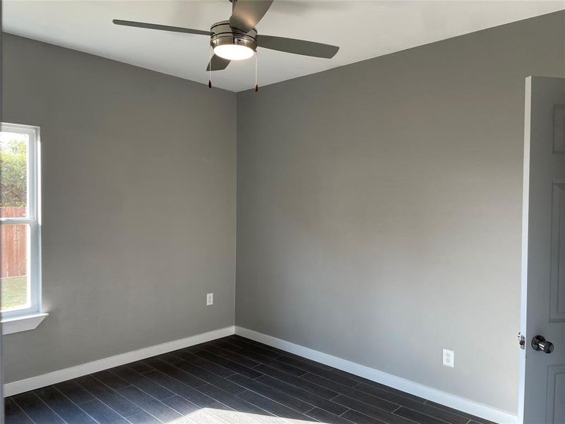 Spare room with ceiling fan, a wealth of natural light, and dark hardwood / wood-style floors