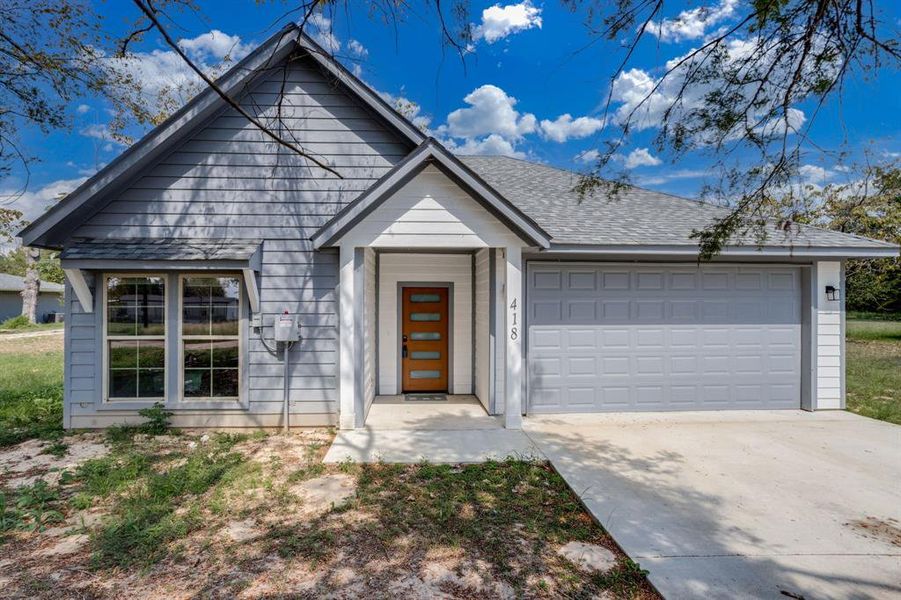 View of front of property with driveway, an attached garage, and a shingled roof View of front of property with driveway, an attached garage, and a shingled roof