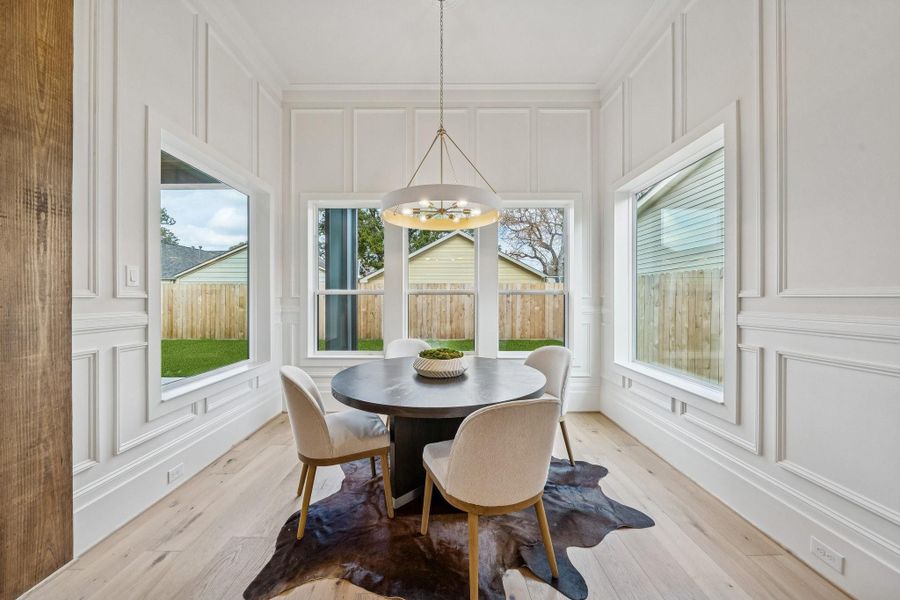 A dining room surrounded by windows to the back yard. This room is outfitted with box moldings as well.