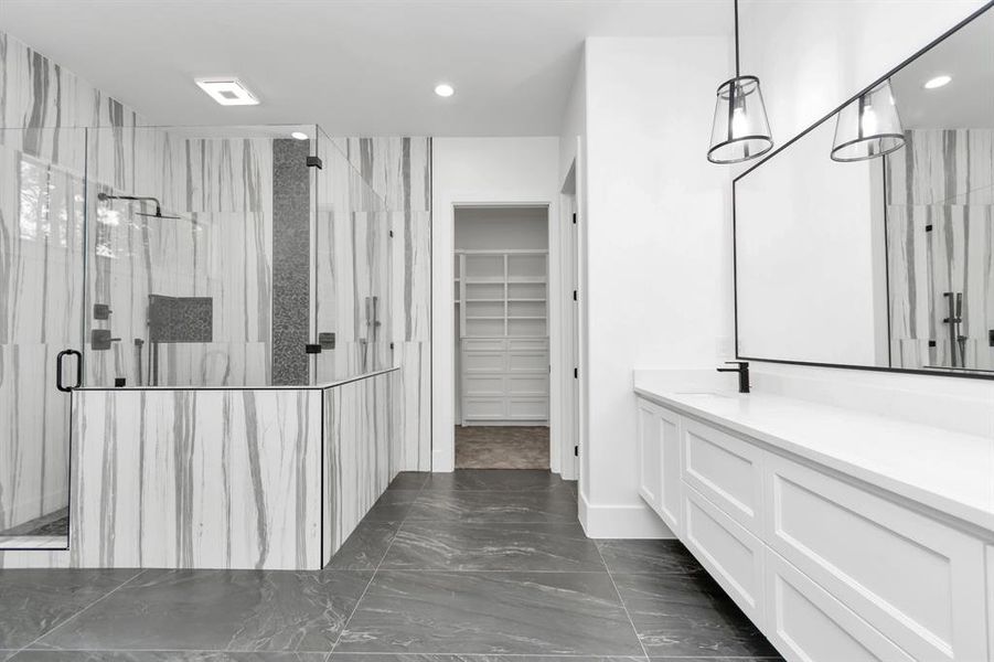 Modern bathroom featuring marble-like tiles, glass-enclosed shower, double vanity with large mirror, and elegant pendant lighting.