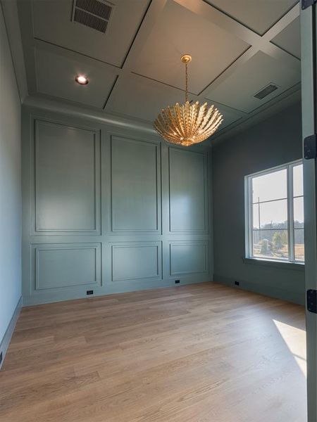 Paneled walls and ceiling in study with designer paint and decorative lighting.