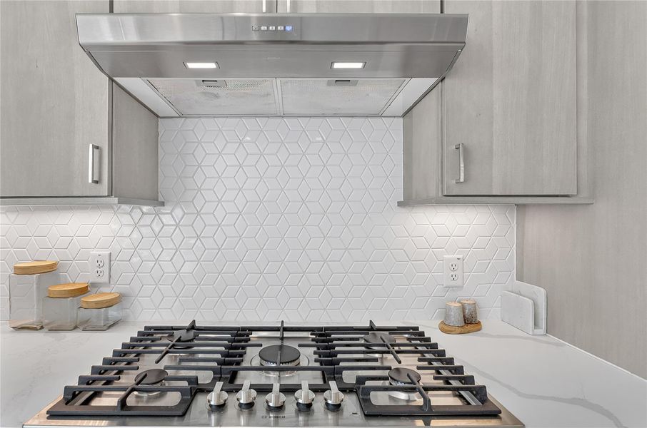 Culinary delights await with this modern gas range and geometric tiled backsplash.
