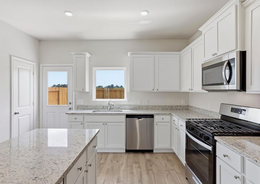 Kitchen featuring white cabinetry, granite countertops, and a stainless microwave.