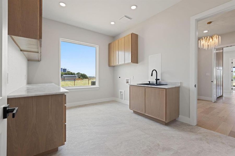 Washroom with cabinet space, hookup for a
washing machine, electric dryer hookup, recessed
lighting, and a chandelier Washroom with cabinet space, hookup for a
washing machine, electric dryer hookup, recessed
lighting, and a chandelier