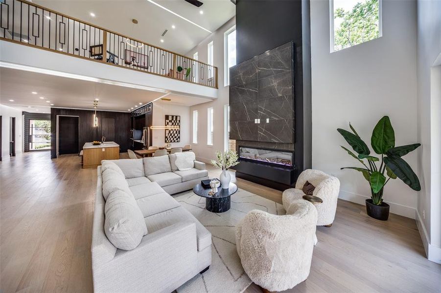 Living room featuring a high end fireplace, a towering ceiling, and light wood-type flooring