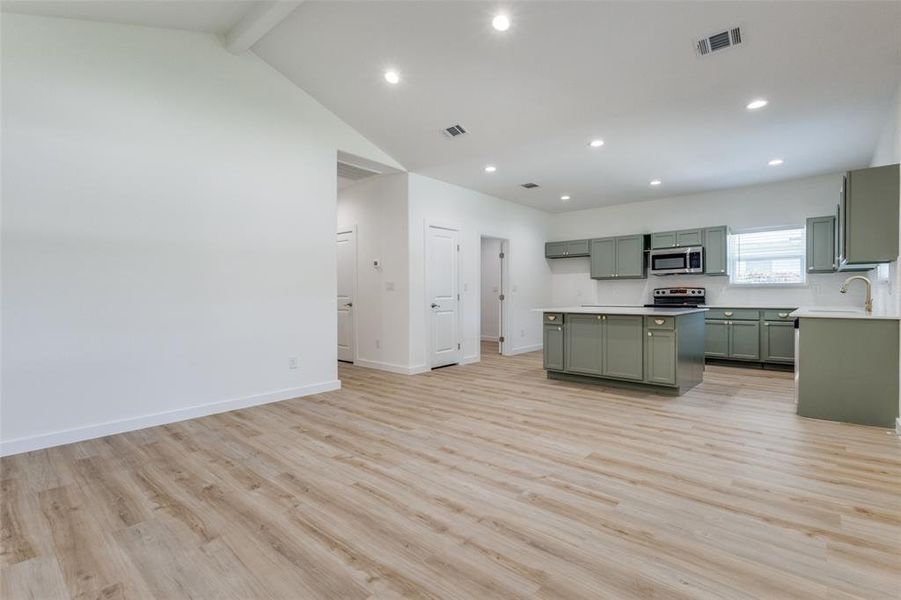 Kitchen with beamed ceiling, stainless steel appliances, sink, light wood-type flooring, and green cabinets