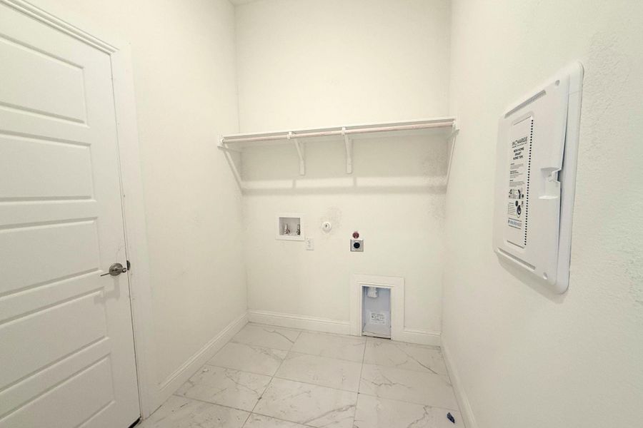 Laundry area featuring white walls, white trim, and white paneled door Laundry area featuring white walls, white trim, and white paneled door