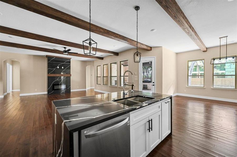 Kitchen with beamed ceiling, dishwasher, sink, an island with sink, and dark wood-type flooring