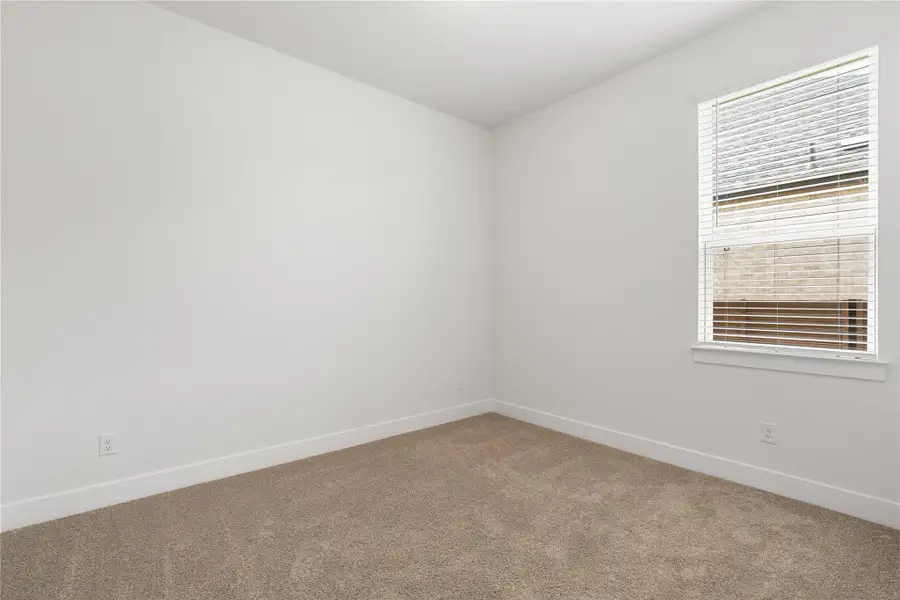 A well-lit bedroom features plush carpeting and a large window with privacy blinds. A well-lit bedroom features plush carpeting and a large window with privacy blinds.