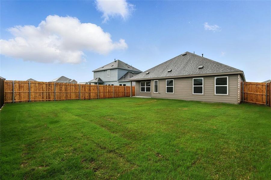 Back of property with a fenced backyard and a shingled roof