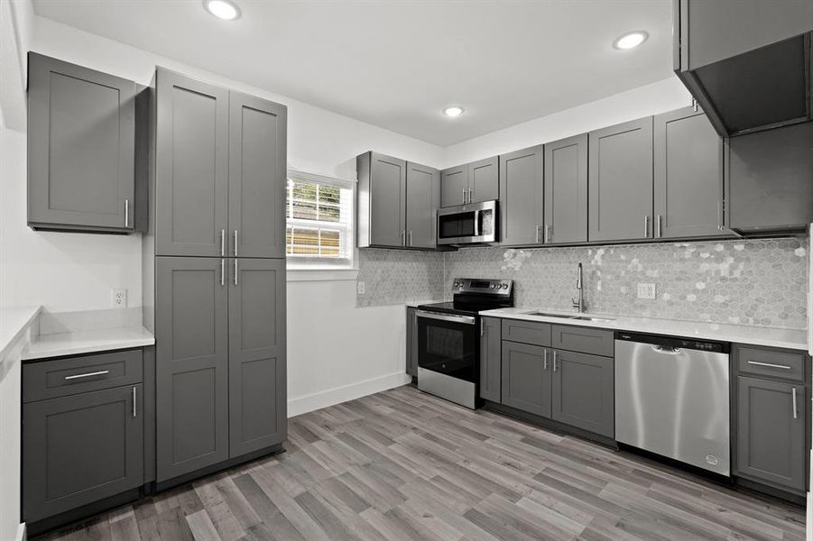 This kitchen features an abundance of new cabinetry and hardware, new granite countertops, new vinyl floors, and recessed lighting.