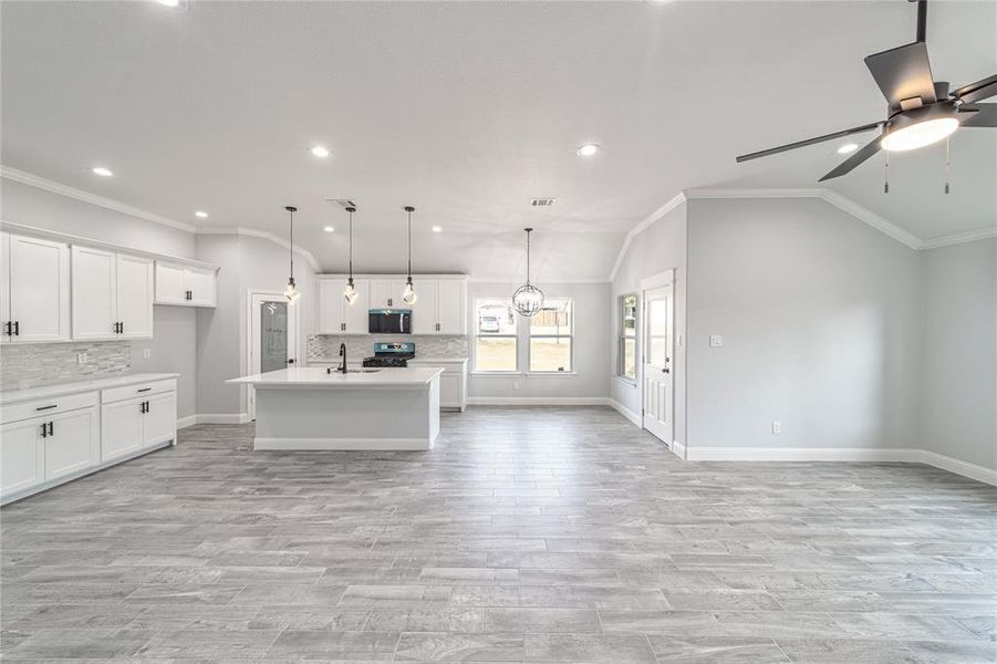 Kitchen with stainless steel appliances, a sink, open floor plan, vaulted ceiling, and light countertops