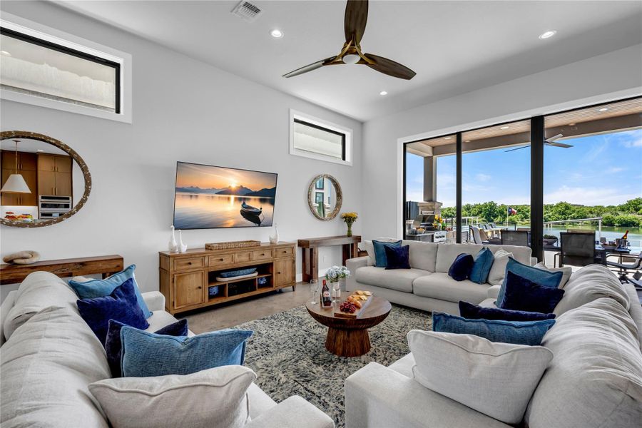 Open-concept living area featuring a vaulted ceiling with a modern ceiling fan, recessed lighting, and expansive glass sliding doors