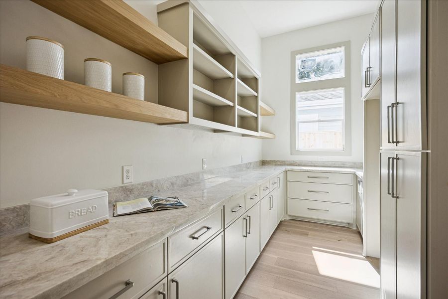 This hidden pantry is every bit as polished as the kitchen, with Taj Mahal counters, custom finishes, oversized drawers and floor to ceiling storage. Hidden behind flush custom cabinetry panels, the high capacity walk-in space offers plenty of room for prep and dry goods, plus dedicated space and electrical connections for a 2nd full refrigerator or freezer, keeping everyday life organized and entertaining easy.