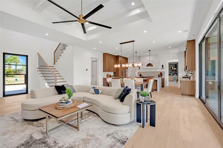 Living room featuring light wood finished floors, recessed lighting, a ceiling fan, stairs, and a chandelier Living room featuring light wood finished floors, recessed lighting, a ceiling fan, stairs, and a chandelier