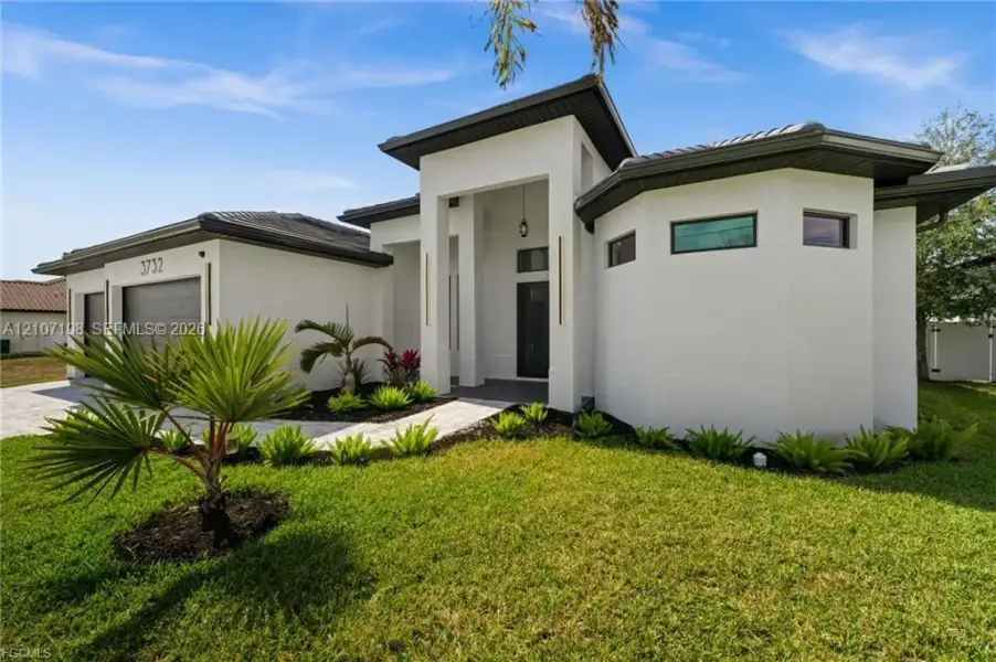 Modern exterior featuring a smooth stucco facade, high-contrast dark roofing, geometric architectural lines, a covered recessed entryway, and a paved driveway