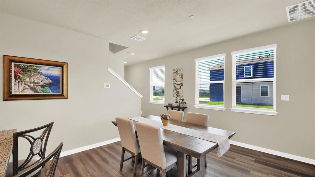 Dining area featuring wood-finish flooring, three windows with white blinds, and recessed ceiling lighting