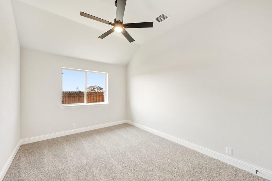 Empty bedroom with vaulted ceiling, ceiling fan, carpet flooring, and a single window Empty bedroom with vaulted ceiling, ceiling fan, carpet flooring, and a single window
