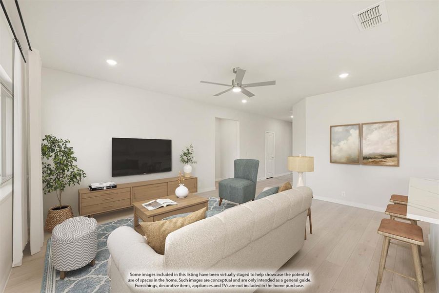 Living room with light wood floors, ceiling fan, neutral sofa, and wall-mounted TV on a wood media console