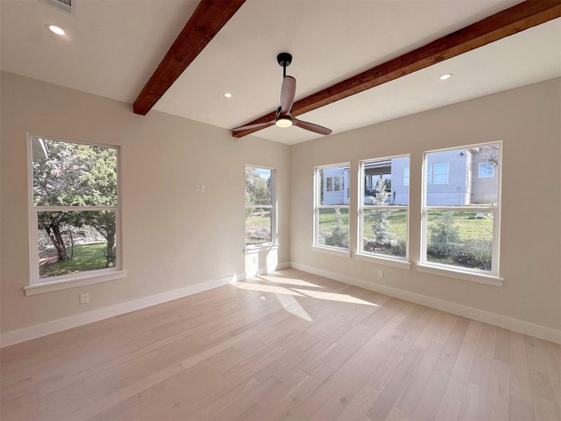 Master bedroom with 10 ft ceilings, recessed lighting, light oak hardwood floors, modern ceiling fan, large windows and solid beam ceiling