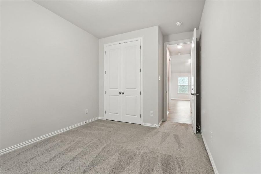 Unfurnished bedroom featuring light carpet and a closet