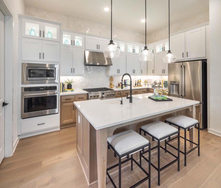 Kitchen with a breakfast bar, white cabinets, light wood-style floors, under cabinet range hood, and appliances with stainless steel finishes