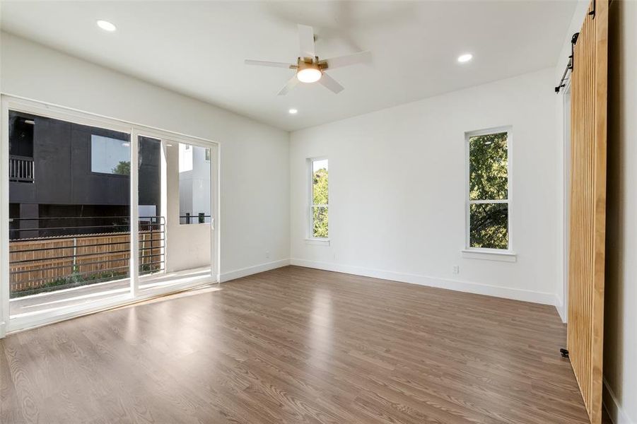 Spare room with wood finished floors, recessed lighting, a barn door, and ceiling fan Spare room with wood finished floors, recessed lighting, a barn door, and ceiling fan