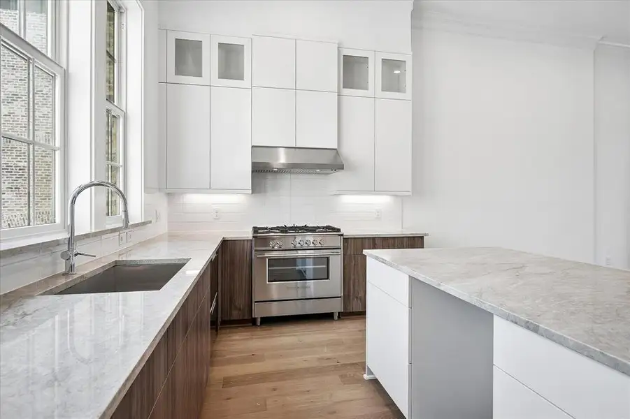 Bright kitchen featuring an integrated gas range, stainless steel appliances, a deep basin sink, and a large central island Bright kitchen featuring an integrated gas range, stainless steel appliances, a deep basin sink, and a large central island
