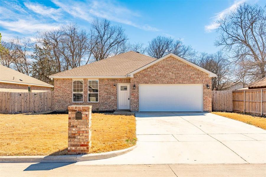 Ranch-style house featuring driveway, an attached garage, fence, and brick siding