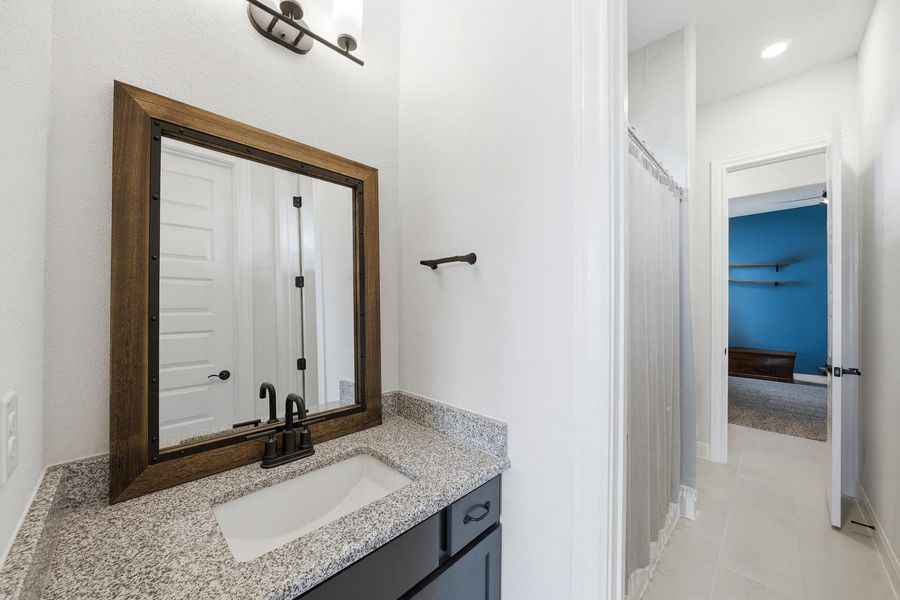 A well-appointed bathroom features a dark wood framed mirror and granite countertops. A well-appointed bathroom features a dark wood framed mirror and granite countertops.