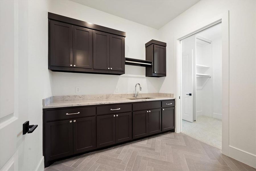 Kitchen featuring light parquet flooring, sink, and dark brown cabinetry