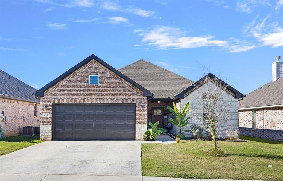 View of front facade with a front lawn, central AC unit, and a garage