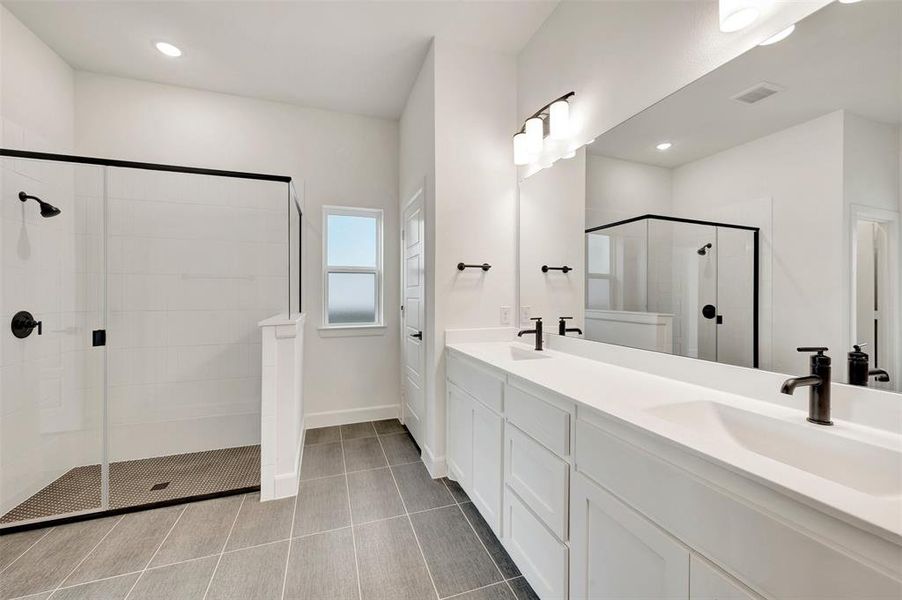 Spacious bathroom featuring a dual vanity with white cabinetry and countertops, matte black plumbing fixtures, a large frameless mirror, and a walk-in shower with clear glass enclosure and black trim