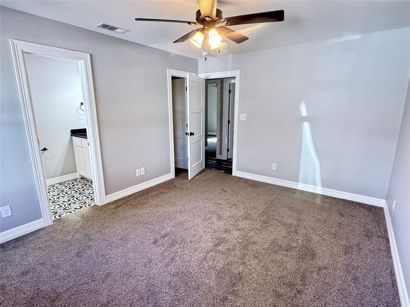 Unfurnished bedroom with carpet flooring, a ceiling fan, and ensuite bath Unfurnished bedroom with carpet flooring, a ceiling fan, and ensuite bath