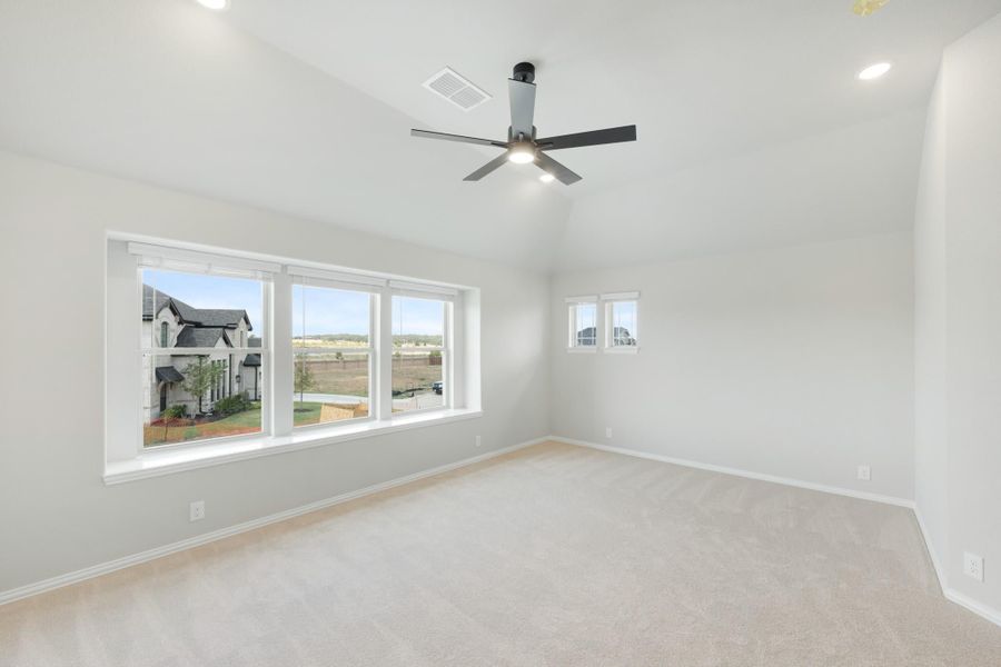 Empty bedroom with carpet, ceiling fan, and large windows overlooking a neighborhood Empty bedroom with carpet, ceiling fan, and large windows overlooking a neighborhood