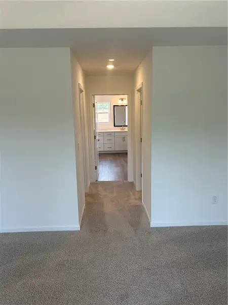 A well-lit corridor leads to a pristine bathroom w