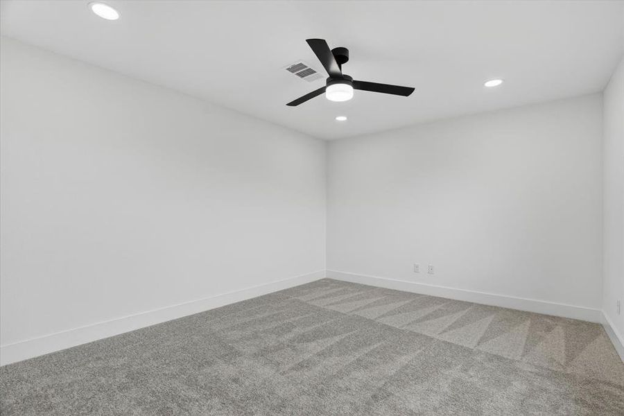 Spacious room featuring light gray carpeting with a subtle geometric pattern, recessed lighting, a contemporary ceiling fan with integrated light, white baseboards, and neutral wall tones