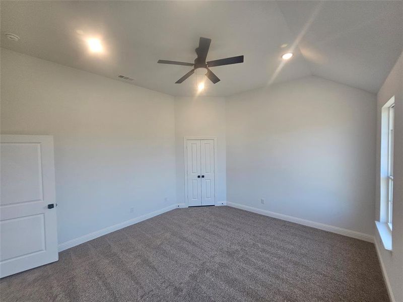 Spare room featuring lofted ceiling, dark carpet, and ceiling fan