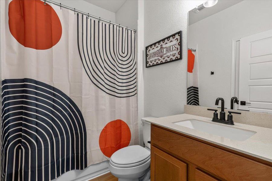 Functional full bathroom, complete with a shower, toilet, and double vanity.