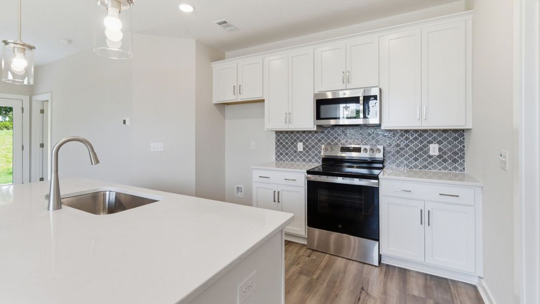 Kitchen with tile backsplash, pendant lighting, and quartz countertops