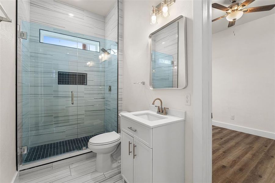 Full bath featuring a stall shower, vanity, and ceiling fan Full bath featuring a stall shower, vanity, and ceiling fan