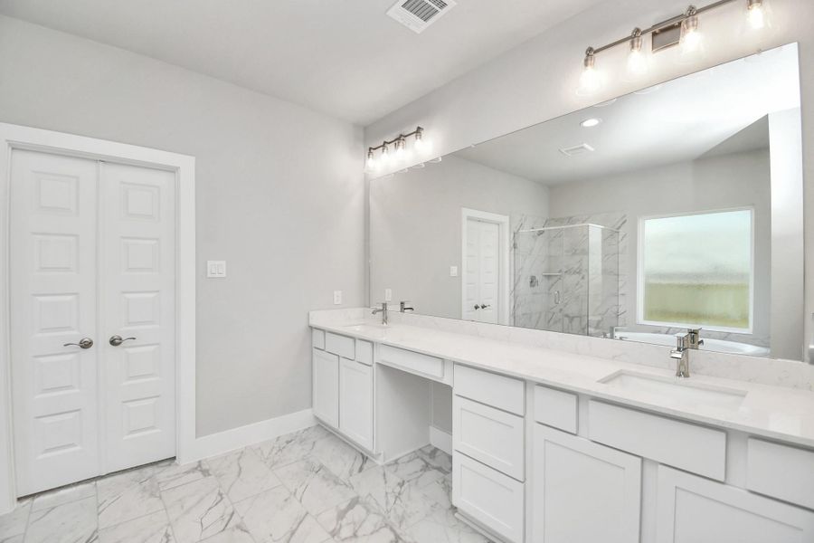 Elevate your daily routine at the elegant vanity, now equipped with double sinks, light countertops, modern hardware, and beautiful vanity lights. Sample photo of completed home with similar floor plan. Actual colors and selections may vary.