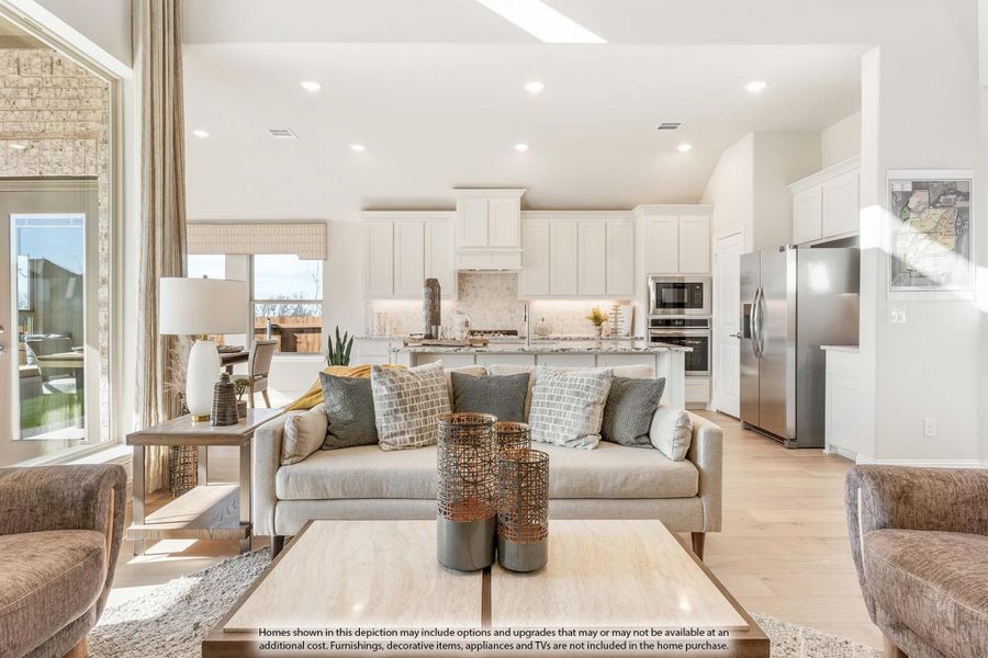 Open-concept living room and kitchen with white cabinets, stainless appliances, and light hardwood floors Open-concept living room and kitchen with white cabinets, stainless appliances, and light hardwood floors