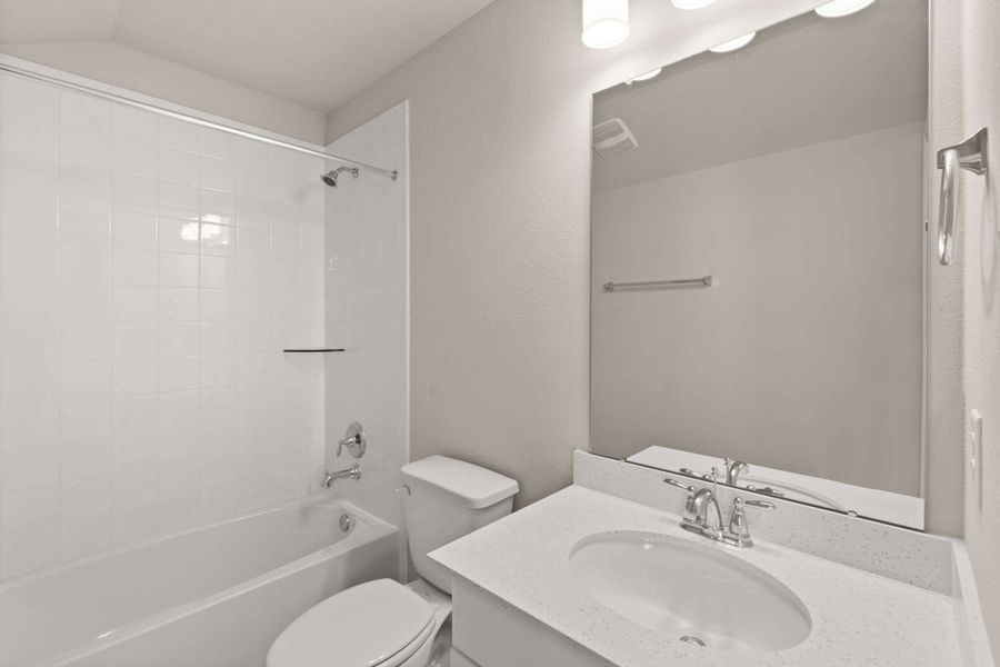 The private bath features tile flooring, white cabinetry with quartz countertops and a shower/tub combo.