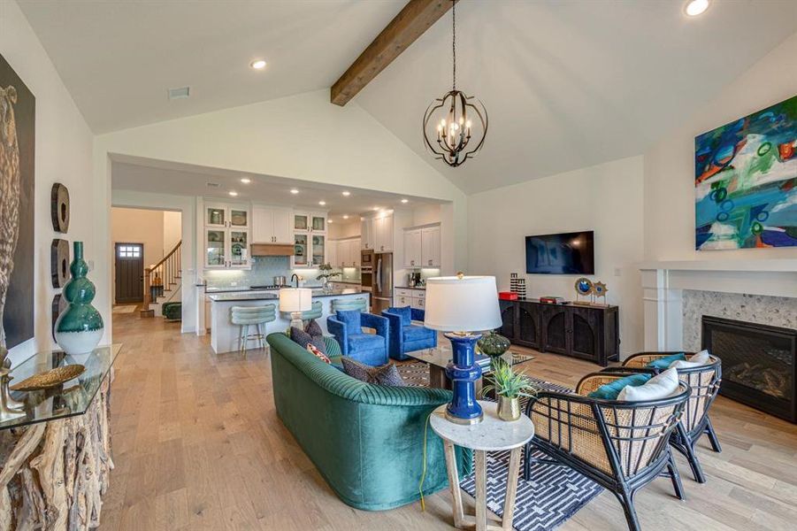 Living room featuring an inviting chandelier, high vaulted ceiling, beamed ceiling, and light hardwood / wood-style flooring