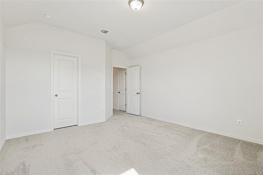 Unfurnished bedroom with light colored carpet and lofted ceiling Unfurnished bedroom with light colored carpet and lofted ceiling