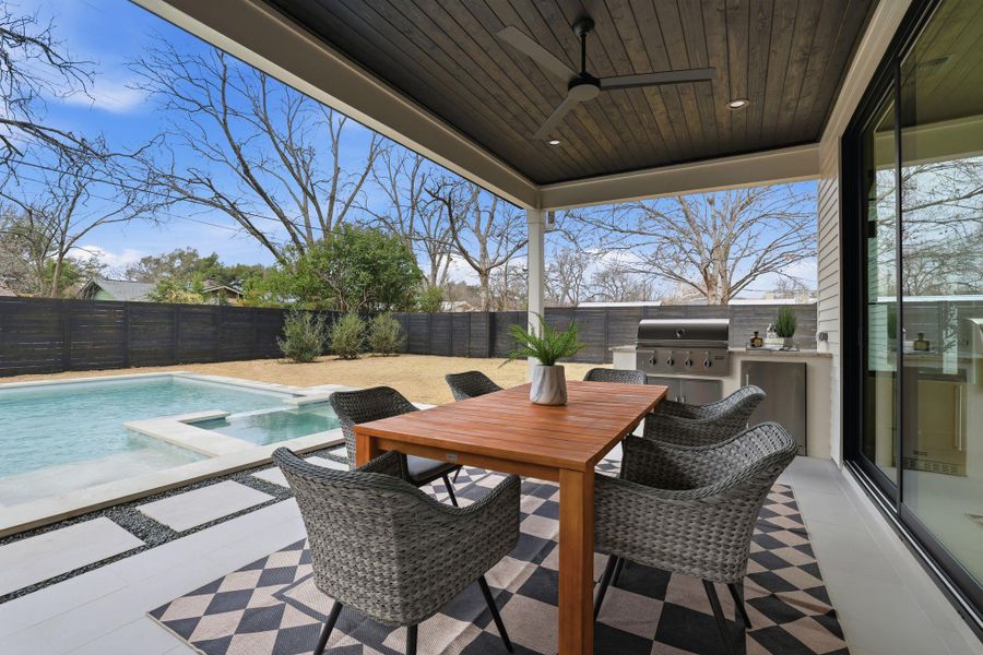 Fenced backyard featuring an outdoor kitchen / dining area, a patio area, a ceiling fan, and a pool with connected hot tub