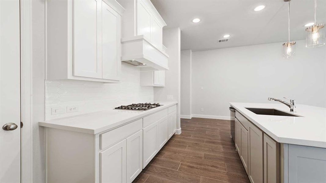 Kitchen with white cabinetry, dark wood-type flooring, tasteful backsplash, pendant lighting, and sink