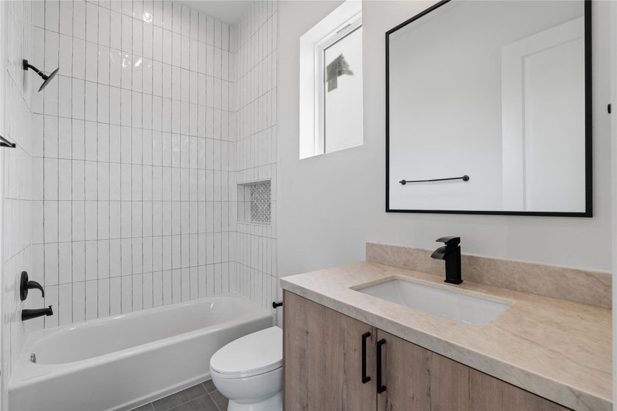 The ensuite guest bathroom features vertical stacked tile with a built-in shampoo niche and large format floor tiles for a clean, modern finish. The ensuite guest bathroom features vertical stacked tile with a built-in shampoo niche and large format floor tiles for a clean, modern finish.