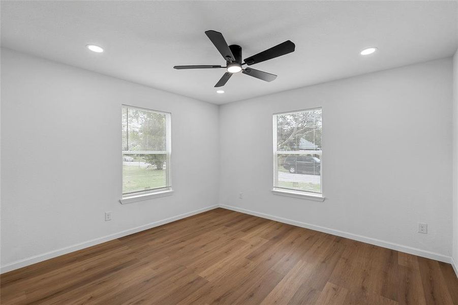 Room featuring wood-finish flooring, two windows, recessed lighting, and a ceiling fan with integrated light Room featuring wood-finish flooring, two windows, recessed lighting, and a ceiling fan with integrated light